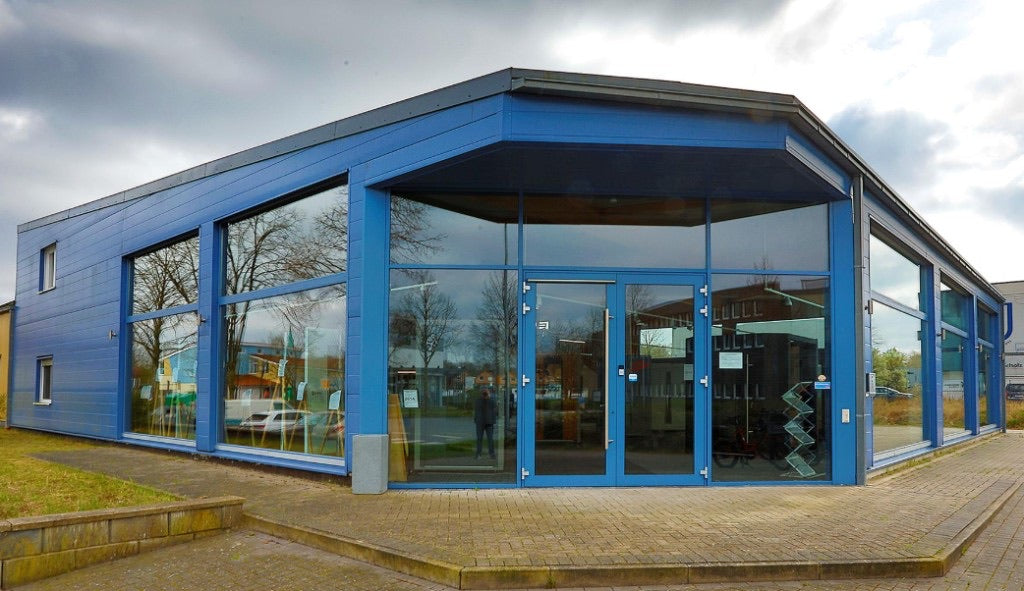 Gebäude der FM Türen GmbH in Kamen, blaue Fassade mit verglaster Front und Eingang, davor ein gepflasterter Vorplatz